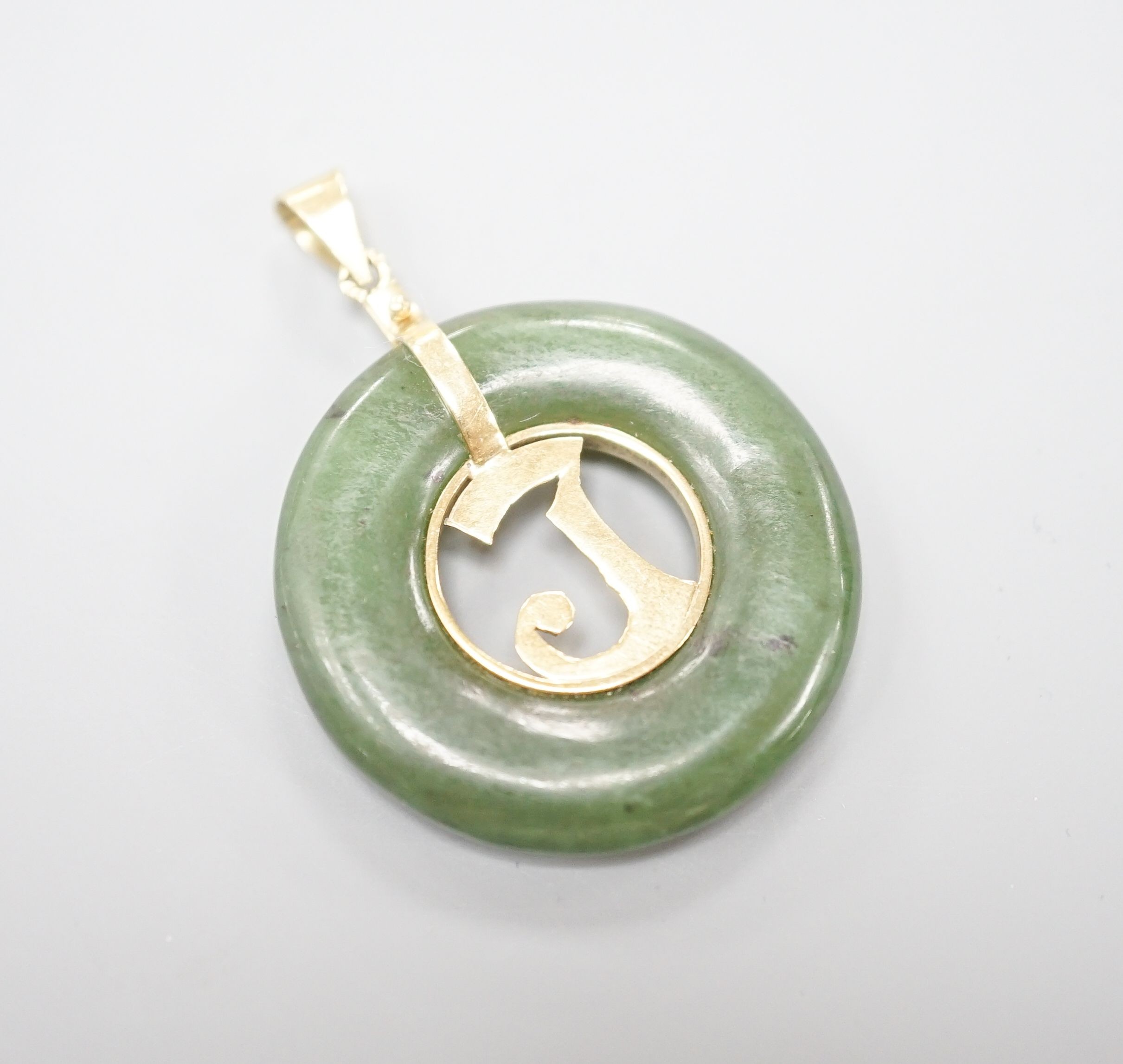 A yellow metal mounted pierced circular nephrite pendant, diameter 29mm, gross weight 8.5 grams.